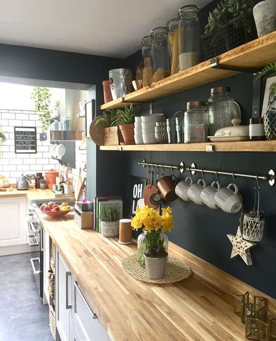 Wooden countertop with white cabinets and black wall kitchen design