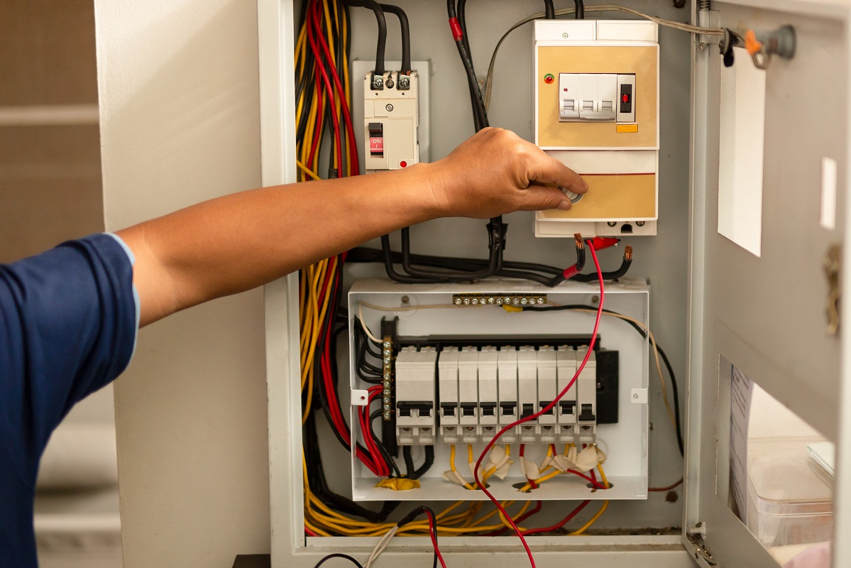 Senior electrician measuring voltage in fuse board