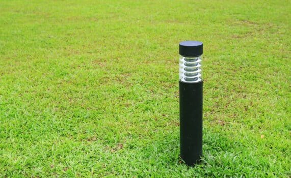 Close up pole of lamp in green grass field.