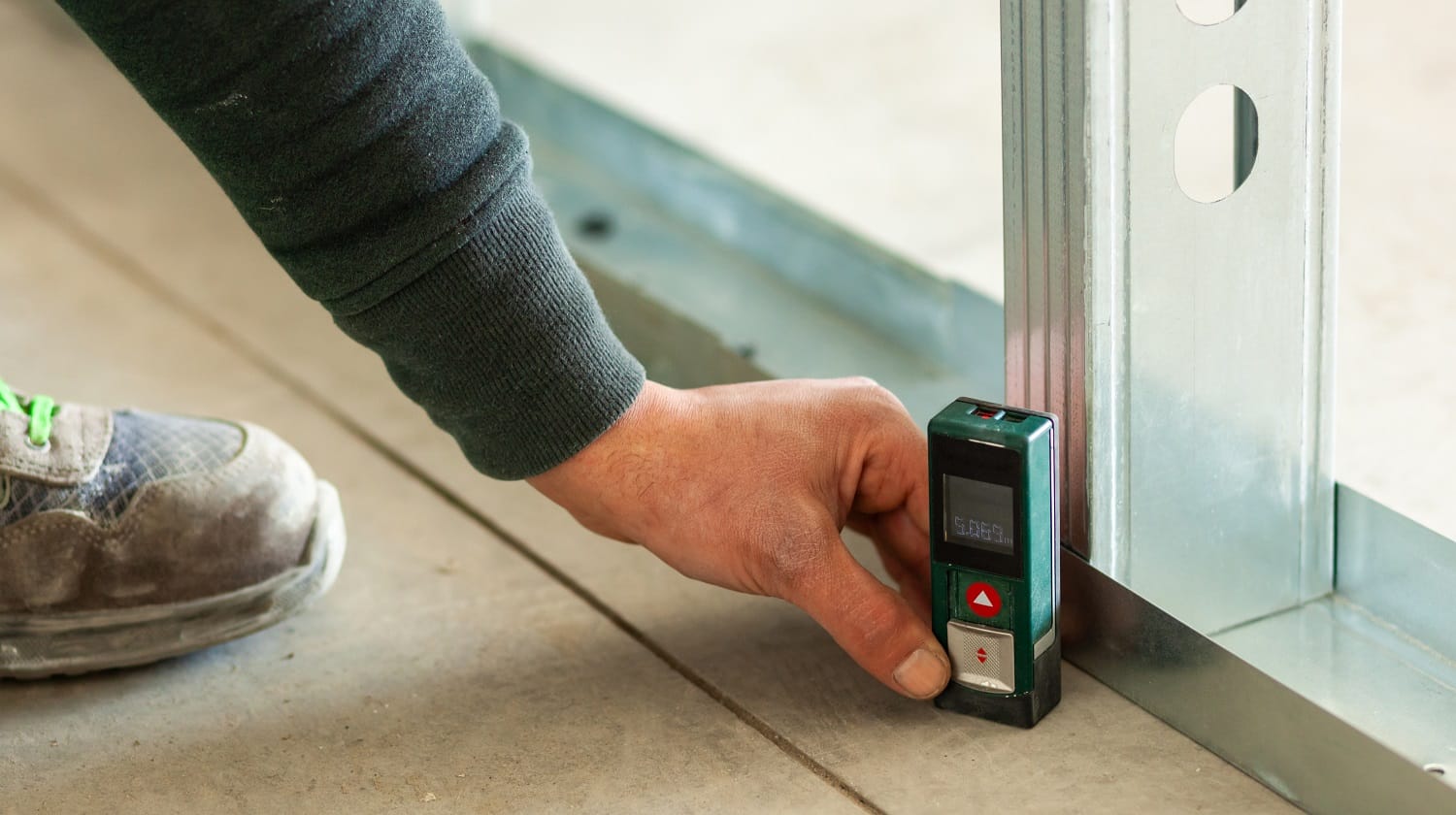 Hand holding an accurate laser meter receiver on the floor.