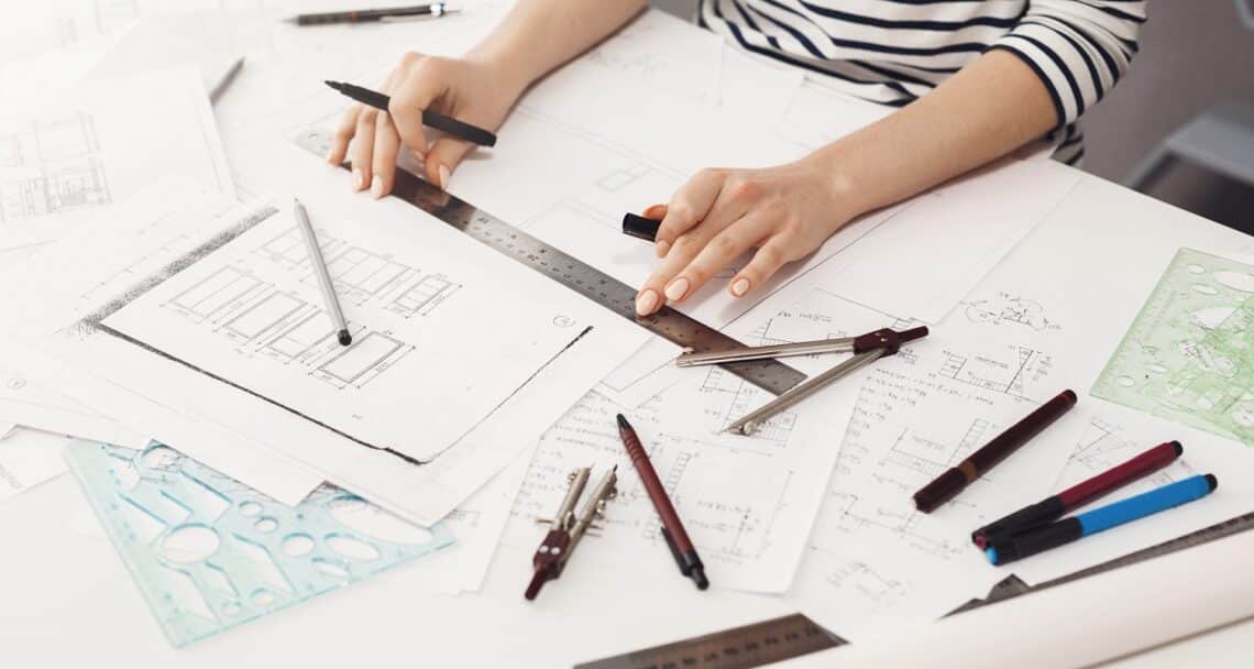 Close up detail of young professional female engineer hands making edits with ruler and liner in new team project. Teamwork and business