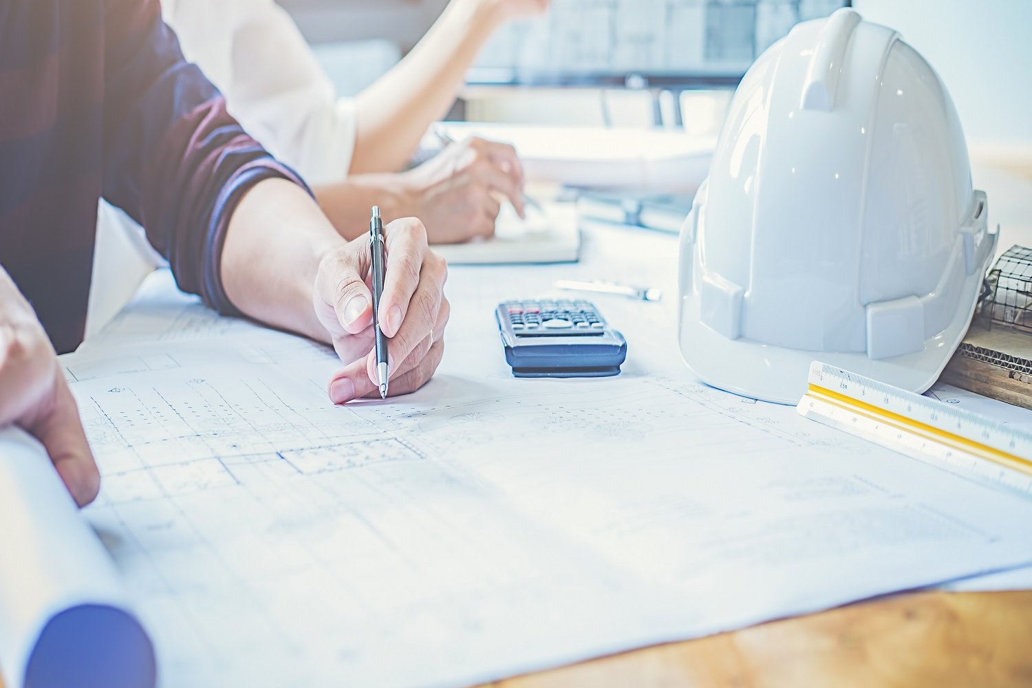 Serious concentrated man draws sketches, prepares blueprint, uses modern tablet, sits at home, isolated over grey background. Professional young male engineer with stubble being in modern office