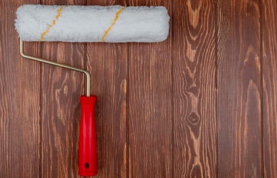 Top view of paint roller on wooden background with copy space