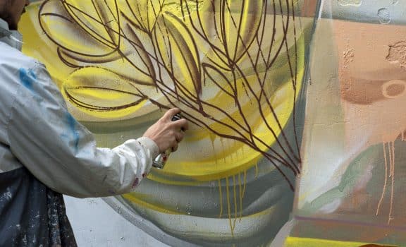 Graffiti artist paints colorful graffiti on a concrete wall. Modern art, urban concept.