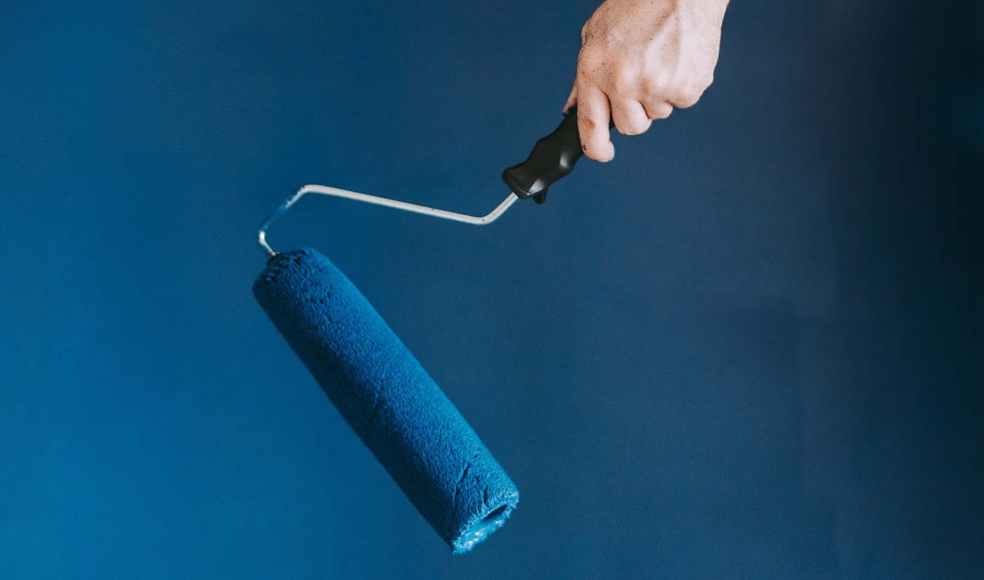 A closeup shot of a female using paint rollers with the color blue