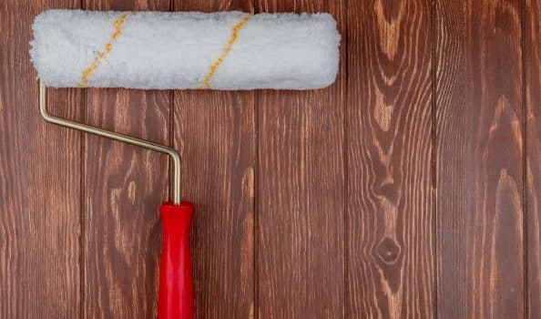 Top view of paint roller on wooden background with copy space