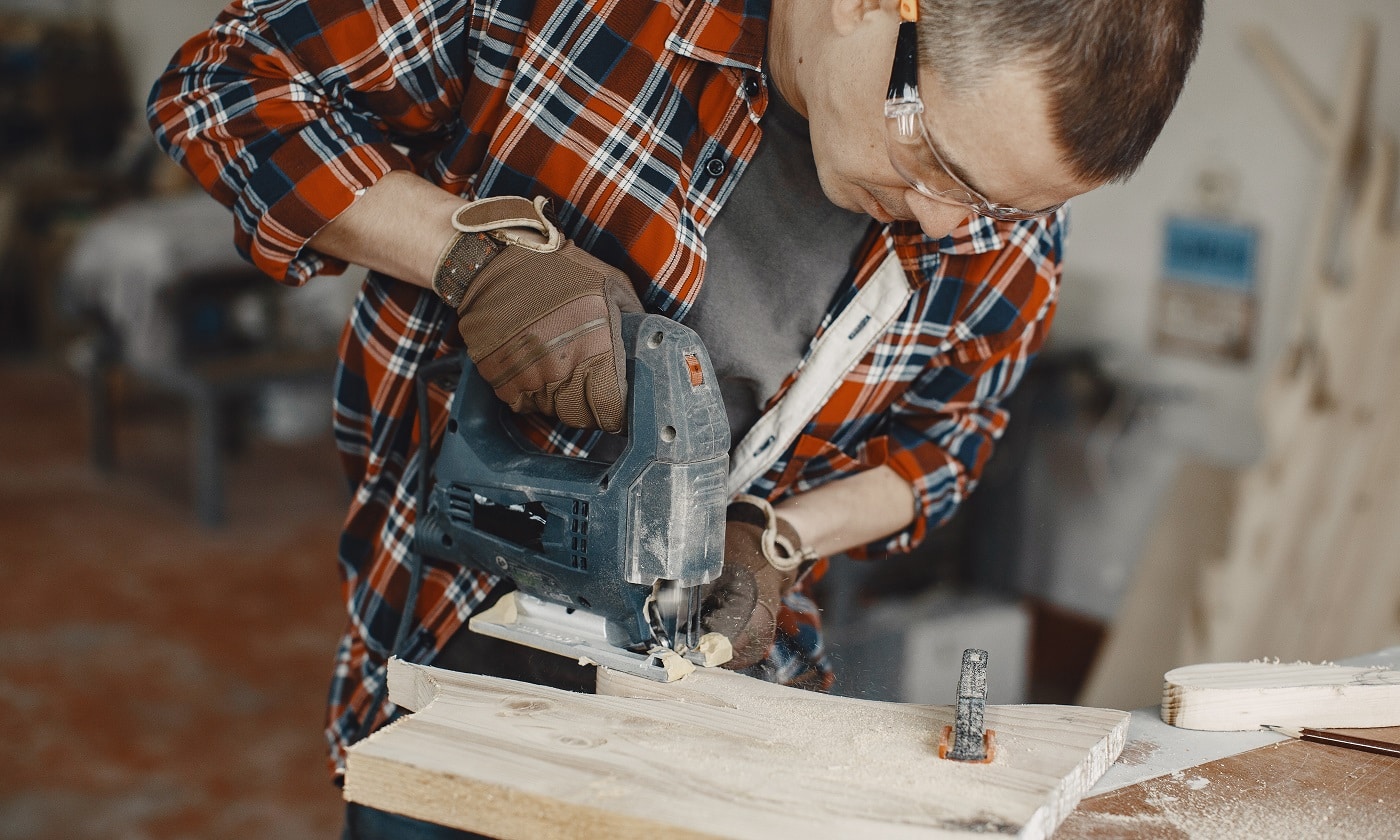 Wood cutting with circular saw. Closeup of mature man sawing lumber.