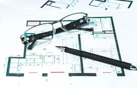 Elegant glasses and pen on a schematic plan for the reconstruction of the room. Architectural concept