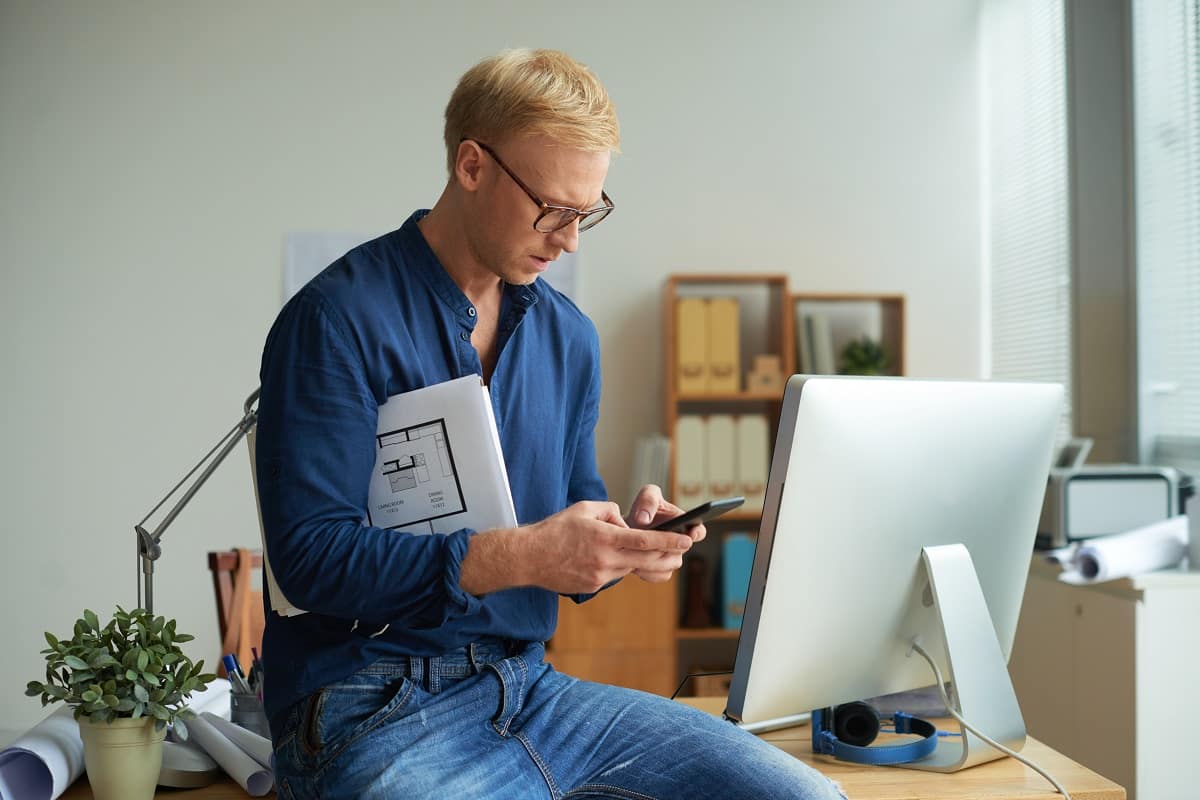 Anxious architect with housing project under his arm texting to client best apps for architects