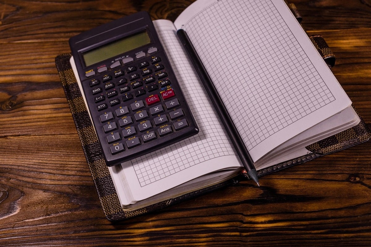 Opened notepad, scientific calculator and pencil on rustic wooden table. Best calculator for sat.