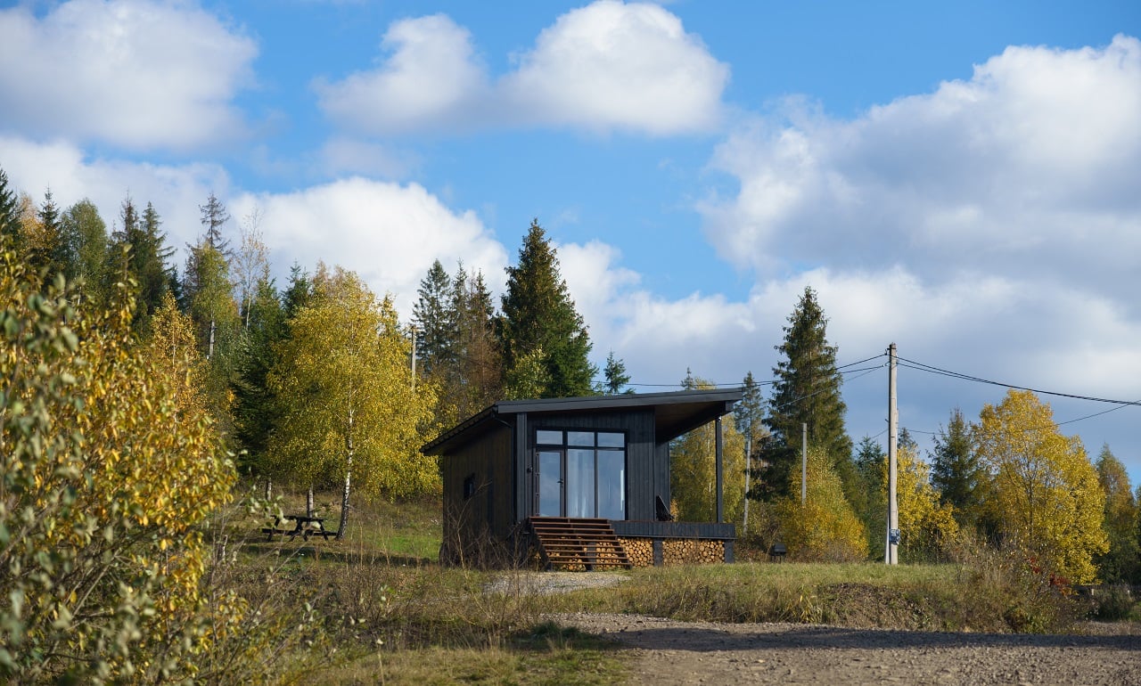 Black wooden cabin in colorful forest in autumn. Modern sjeds.