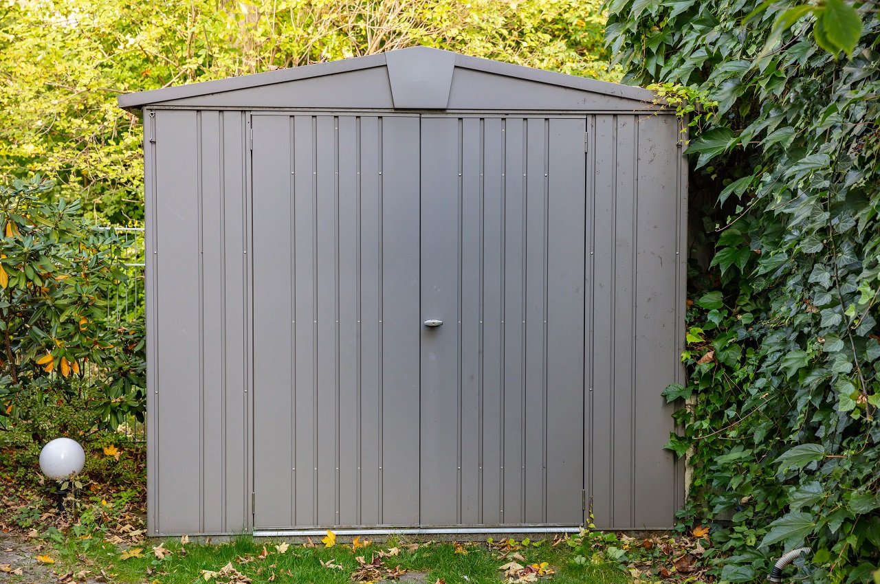 Gardening tools storage shed in the house backyard. Sheet metal sheds.