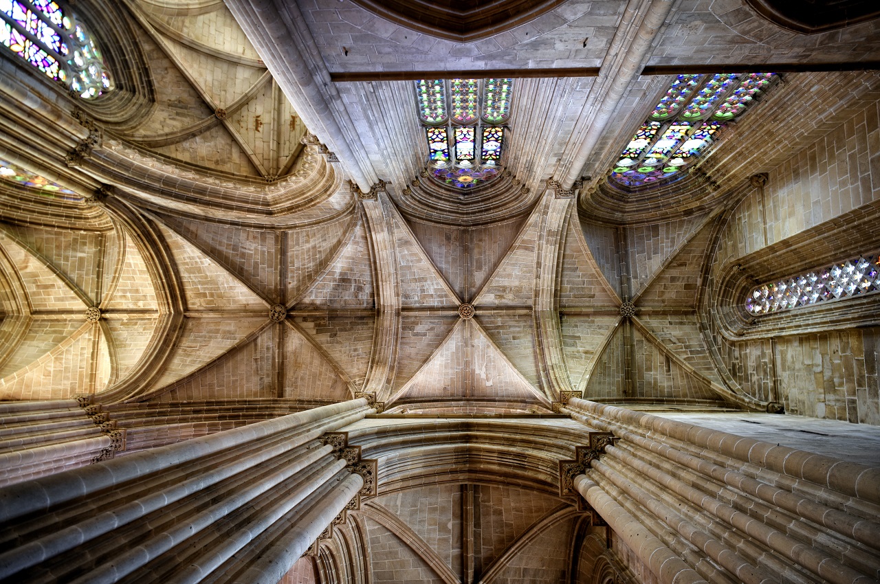 A low angle shot of the ceiling in the interior of a historic cathedral with arches and stained glass window. Final thoughts.